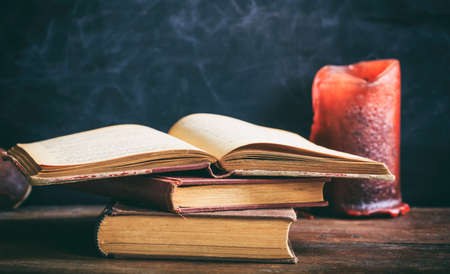 Vintage books and candle on blackboard background - copy spaceの写真素材