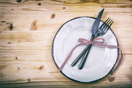 Table setting with plate, fork and knife on wooden background