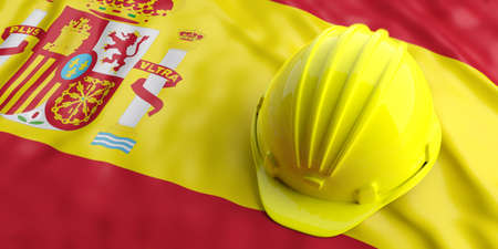 Yellow construction hat over Spain flag. 3d illustrationの写真素材