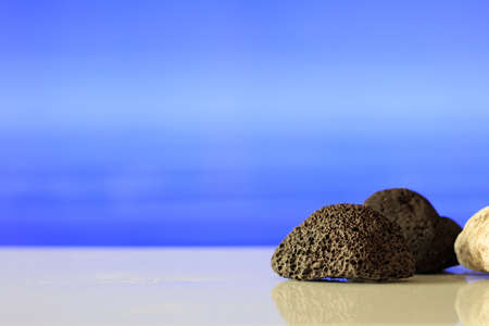 Black and white pumice stones on blue sea backgroundの写真素材