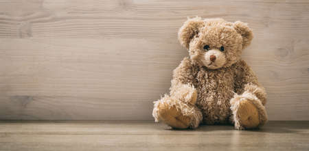 Teddy bear sitting on a wooden backgroundの写真素材
