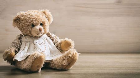 Teddy bear sitting on a wooden backgroundの写真素材