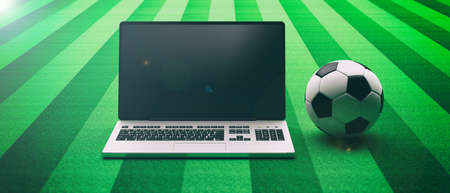 Soccer football ball and a computer on an illumunated field grass background. 3d illustrationの写真素材