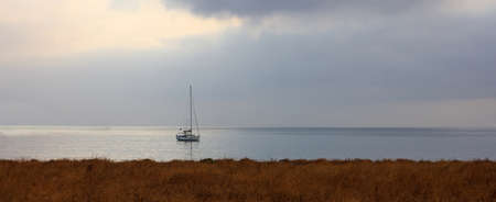 Sailing boat on a cloudy sky backgroundの写真素材
