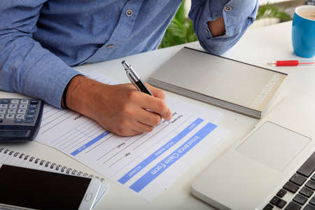 Man fillimg an Insurance Claim Form in an office backgroundの写真素材