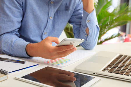 Man holding a smartphone in an office backgroundの写真素材