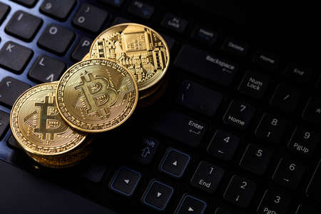 Golden bitcoins on a black computer keyboardの写真素材