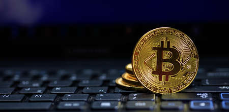 Golden bitcoin on a black computer keyboard