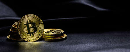 Golden bitcoins stacked on a black texture background