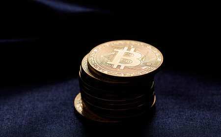 Golden bitcoins stacked on a black texture backgroundの写真素材