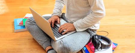 Modern workspace at home. Young man working with a laptop on the wooden floorの写真素材