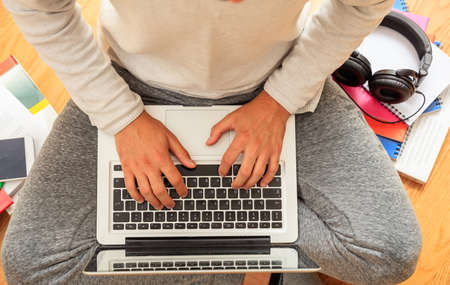 Modern workspace at home. Young man working with a laptop on the wooden floor. Top viewの写真素材