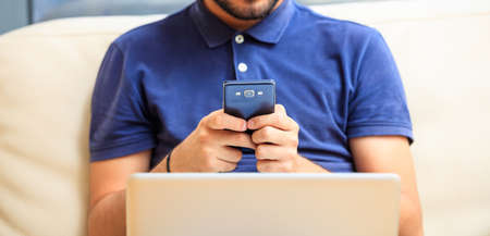 Young man looking at his smart phone, closeup on the handsの写真素材