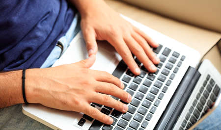 Young man working with a laptop at home, closeup on the handsの写真素材
