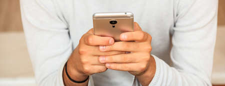 Young man looking at his smart phone, closeup on the handsの写真素材