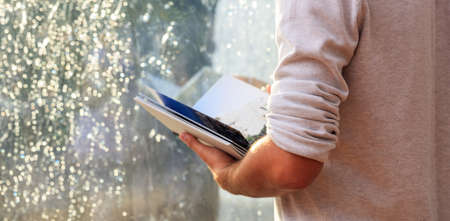Young man holding a book infront of a glass windowの写真素材