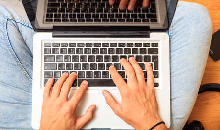 Modern workspace at home. Young man working with a laptop on the wooden floor. Top viewの写真素材