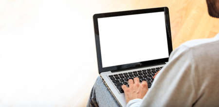 Young man working with a white screen laptop at home, copy spaceの写真素材