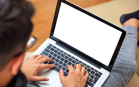 Young man working with a white screen laptop at home, copy spaceの写真素材