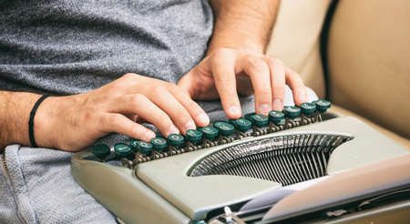 Man typing on a vintage typewriter. Close up on handsの写真素材