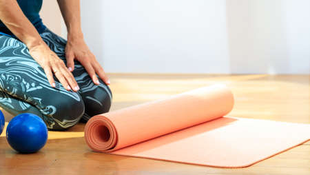 Fitness at home concept. Woman and an exercise mat on wooden floor. Copy spaceの写真素材