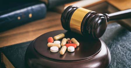 Law gavel and colorful pills on a wooden desk, dark backgroundの写真素材