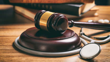 Law gavel and a stethoscope on a wooden desk, dark backgroundの写真素材