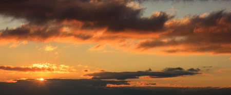 Beautiful sunset on colorful sky. Gold sun lightens the clouds. The sun is on the left side.の写真素材