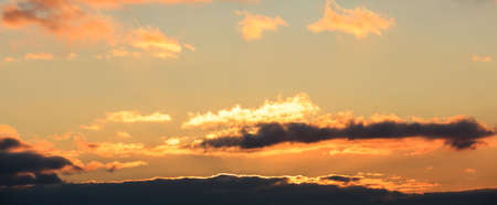 Beautiful sunset on colorful sky. Gold sun hides behind the clouds and lighten them.の写真素材