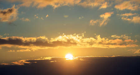 Beautiful sunset on colorful sky. Gold sun lightens the clouds. The sun is in the middle.の写真素材