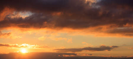 Beautiful sunset on colorful sky. Gold sun lightens the clouds. The sun is on the left side.の写真素材