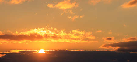Beautiful sunset on colorful sky. Gold sun lightens the clouds. The sun is on the left side.の写真素材