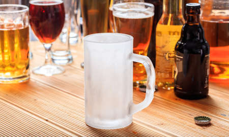 An empty frosty mug of beer on a wooden pub counterの写真素材