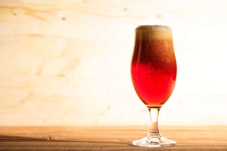 A glass full of red beer on a wooden background, copy spaceの写真素材