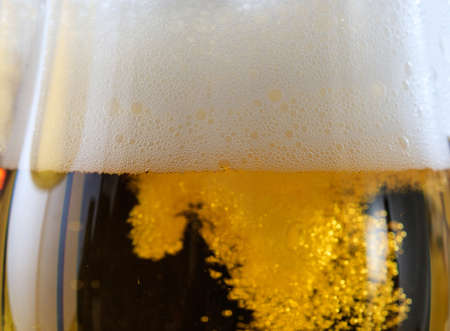 A glass of lager beer detail. Closeup on the beer froth and bubblesの写真素材