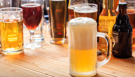 A full frosty mug of beer on a wooden pub counterの写真素材