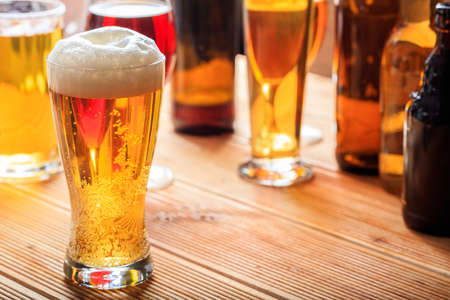 A full frosty glass of beer on a wooden pub counterの写真素材