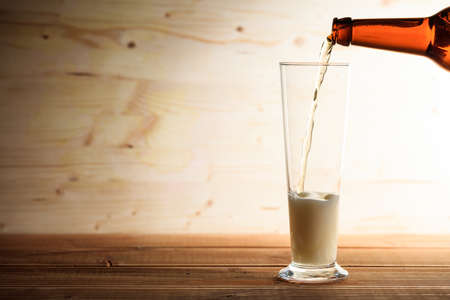 Pouring beer in a glass on a wooden table, Copy spaceの写真素材