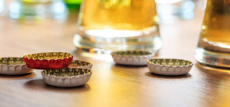 Beer caps and glasses of beer on a pub background. Closeup on the beer capsの写真素材