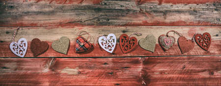 Decorative hearts on red wooden background, top viewの写真素材