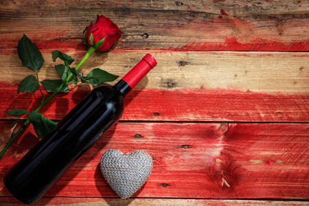 Valentines day concept. Red wine bottle and red rose on wooden backgroundの写真素材