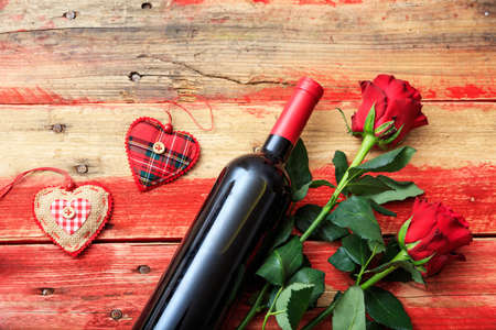 Valentines day concept. Red wine bottle and red roses on wooden backgroundの写真素材
