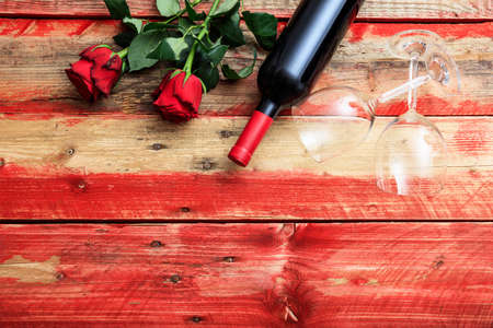 Valentines day concept. Red wine bottle, glasses and roses on wooden backgroundの写真素材