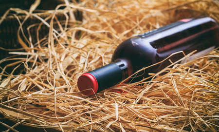 Unopened rose wine bottle on straw backgroundの写真素材