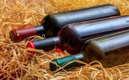 Red, rose and white wine bottles on straw backgroundの写真素材