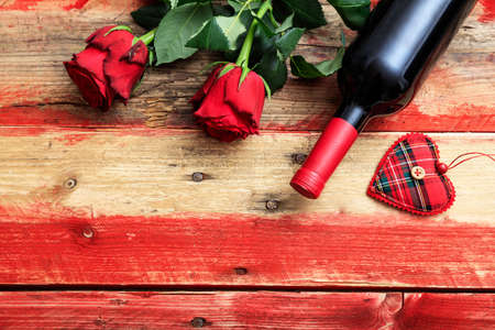 Valentines day concept. Red wine bottle and red roses on wooden backgroundの写真素材