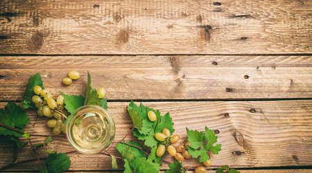 White wine glass and fresh grapes on wooden background, top view, copy spaceの写真素材