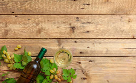 White wine glass and bottle and fresh grapes on wooden background, top view, copy spaceの写真素材