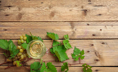 White wine glass and fresh grapes on wooden background, top view, copy spaceの写真素材