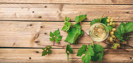 White wine glass and fresh grapes on wooden background, top view, copy spaceの写真素材